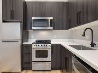 Experience modern living in this sleek kitchen featuring stainless steel appliances, including a Whirlpool refrigerator and microwave.