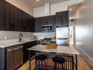 Experience modern living in this sleek kitchen featuring dark wood cabinetry and a stunning marble-look island with bar seating.