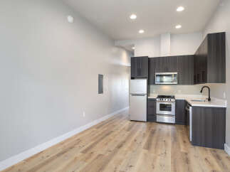 Discover modern living in this beautifully appointed studio apartment, featuring a sleek, contemporary kitchen with dark wood cabinetry and stainless steel appliances.