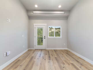 Step into this bright and airy room, featuring a modern aesthetic with light gray walls and a beautiful wood-look laminate floor.