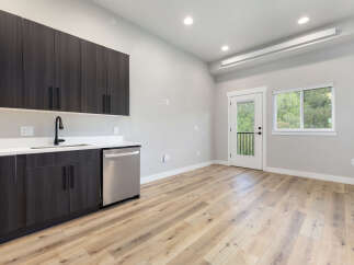 Discover modern living in this stylish space featuring sleek, dark wood cabinetry and a convenient stainless steel dishwasher.