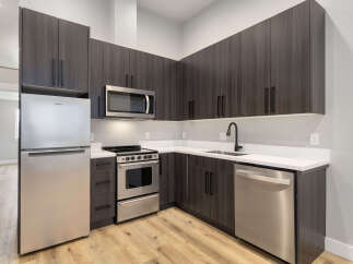 Experience modern living in this sleek kitchen featuring dark wood cabinetry and stainless steel appliances.