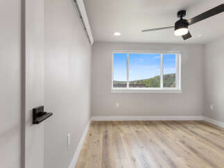 Experience modern living in this beautifully appointed room, featuring a sleek ceiling fan and a large window offering scenic views.