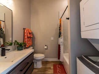 This modern bathroom features a sleek vanity with a dark wood cabinet and a white countertop, complemented by a stylish black faucet.
