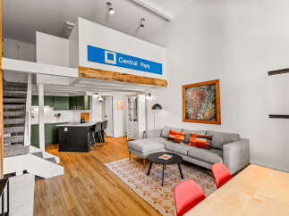 Experience modern living in this stylish loft-style apartment featuring an open-concept living area with a comfortable sectional sofa and a vibrant abstract artwork.