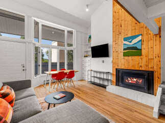 Experience cozy living in this inviting space, featuring a modern fireplace with a striking wood accent wall and a large bay window that floods the room with natural light.