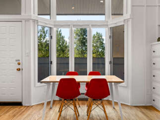 Bright and airy dining area featuring a modern table with four vibrant red chairs, perfect for intimate gatherings.