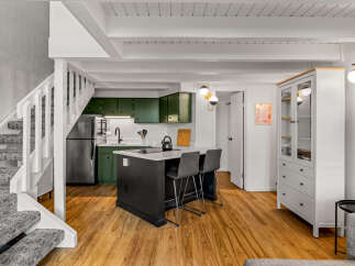 Discover this charming kitchen featuring sleek green cabinetry and a modern island with bar seating, perfect for casual dining.
