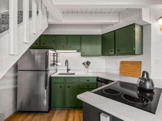 Discover this charming kitchen featuring sleek green cabinetry and a modern stainless steel refrigerator.