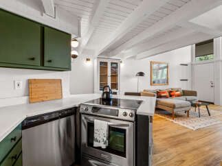 Experience modern living in this open-concept space, featuring a sleek kitchen with green cabinetry and stainless steel appliances.