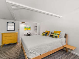 Discover this charming bedroom featuring a comfortable bed adorned with decorative pillows and a light gray quilted comforter.