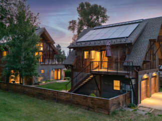 Experience sustainable living in this modern rustic home featuring a prominent solar panel array on the roof.