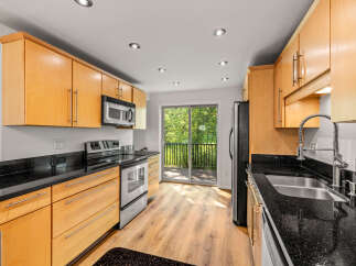 Step into this beautifully updated kitchen featuring sleek light wood cabinetry and durable black granite countertops.