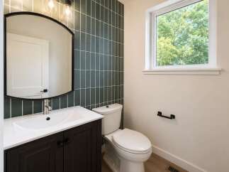 This modern bathroom features a sleek vanity with a white undermount sink and dark wood cabinetry, complemented by a large arched mirror.