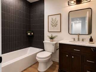 This modern bathroom features a sleek design with dark vertical tile accenting the bathtub and shower area.
