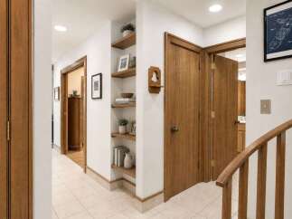 Step into this inviting hallway featuring warm wooden doors and built-in shelving perfect for displaying decor.
