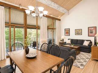 Experience comfortable living in this spacious great room, featuring a vaulted wood-beamed ceiling and expansive windows that flood the space with natural light.