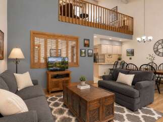 Experience cozy living in this charming living room featuring a comfortable gray sofa and a rustic wooden coffee table.