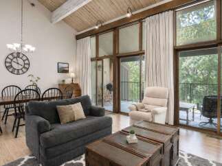 Experience breathtaking natural views from this stunning living area, featuring a vaulted wood-beamed ceiling and expansive windows that flood the space with light.