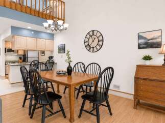 This spacious dining area features a large wooden table with six black chairs, perfect for family gatherings.