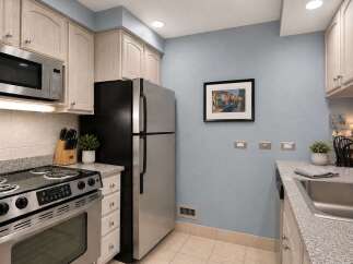 This charming kitchen features light wood cabinetry and a sleek stainless steel appliance suite, including a microwave and refrigerator.