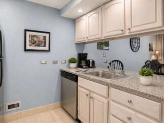 This charming kitchen features light wood cabinetry and a granite countertop, perfect for meal preparation.