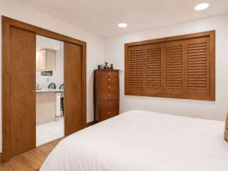 Discover comfort and convenience in this inviting bedroom, featuring a large window with wooden shutters that add a touch of rustic charm.