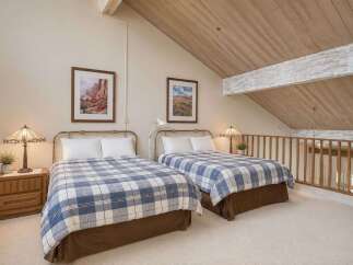 Discover this charming loft bedroom featuring two comfortable beds adorned with classic blue and white plaid comforters.