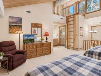 Experience rustic charm and spacious living in this unique bedroom featuring two cozy beds with blue plaid comforters.