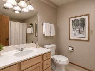 This charming bathroom features a light wood vanity with a cultured marble countertop and a white undermount sink.