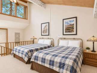 This charming loft bedroom features two comfortable beds adorned with classic blue and white plaid comforters, perfect for a cozy retreat.