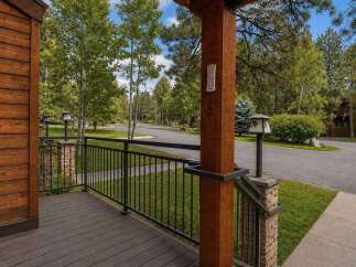 Experience the charm of this mountain home, featuring a welcoming wooden deck and a sturdy railing perfect for enjoying the serene surroundings.