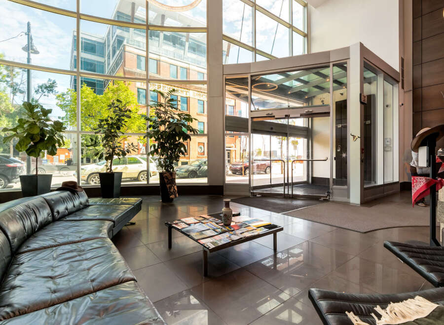 Experience modern comfort in this spacious lobby featuring a sleek, curved black leather sofa and a stylish coffee table adorned with magazines.