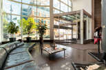 Experience modern comfort in this spacious lobby featuring a sleek, curved black leather sofa and a stylish coffee table adorned with magazines.