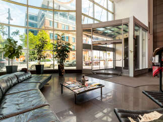 Experience modern comfort in this spacious lobby featuring a sleek, curved black leather sofa and a stylish coffee table adorned with magazines.