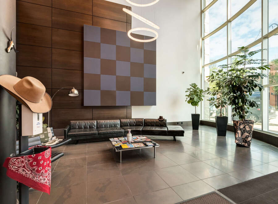 Step into a modern and inviting lobby featuring sleek black leather sofas and a stylish checkered accent wall.