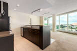 Experience modern living in this spacious condo featuring a sleek, dark wood kitchen island with a stainless steel sink and ample cabinetry.