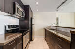 This modern kitchen features dark wood cabinetry and sleek stainless steel appliances, including a microwave, oven, and refrigerator.