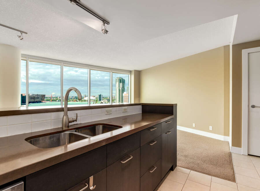 Experience breathtaking city views from this modern kitchen, featuring a sleek double sink and ample counter space.