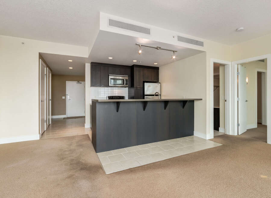 This modern condo features a sleek, dark wood kitchen with stainless steel appliances and a convenient breakfast bar.