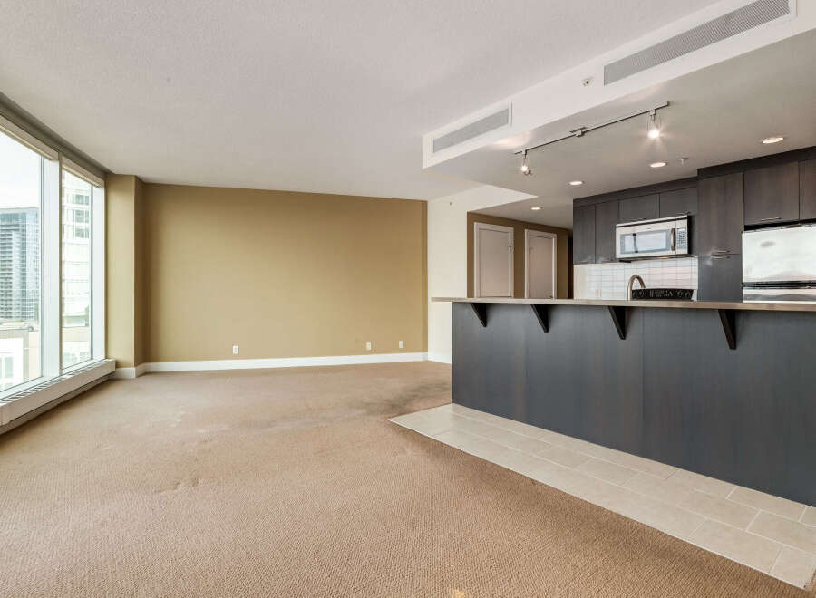 Experience modern living in this spacious open-concept condo, featuring a sleek kitchen with dark cabinetry and a convenient breakfast bar.