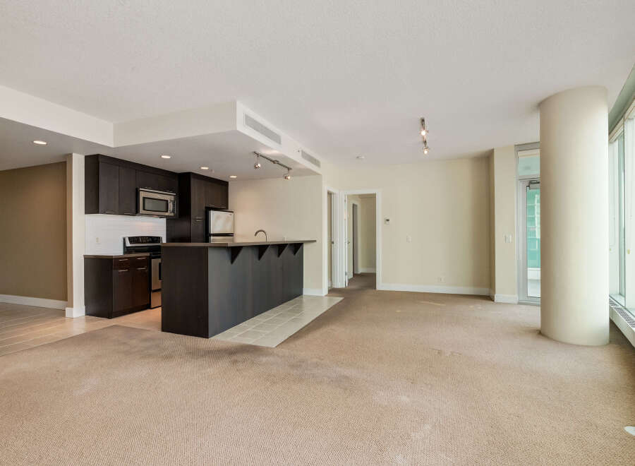 Discover modern living in this spacious open-concept condo, featuring a sleek dark wood kitchen with a convenient breakfast bar.
