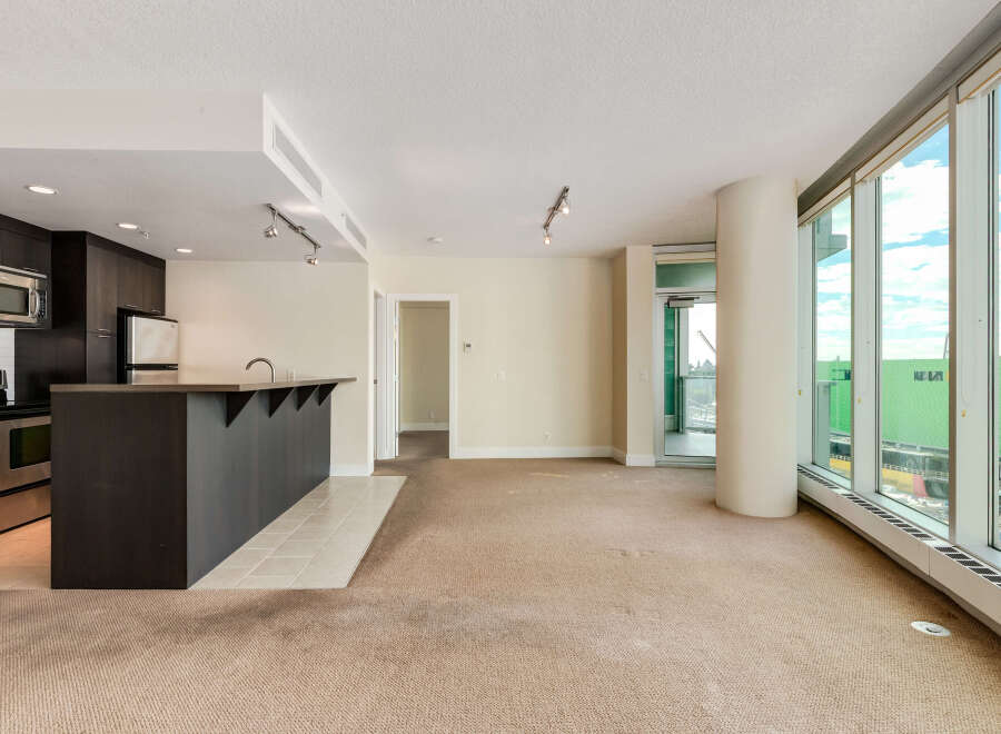 Experience modern living in this spacious open-concept condo featuring a sleek kitchen with dark cabinetry and a convenient breakfast bar.