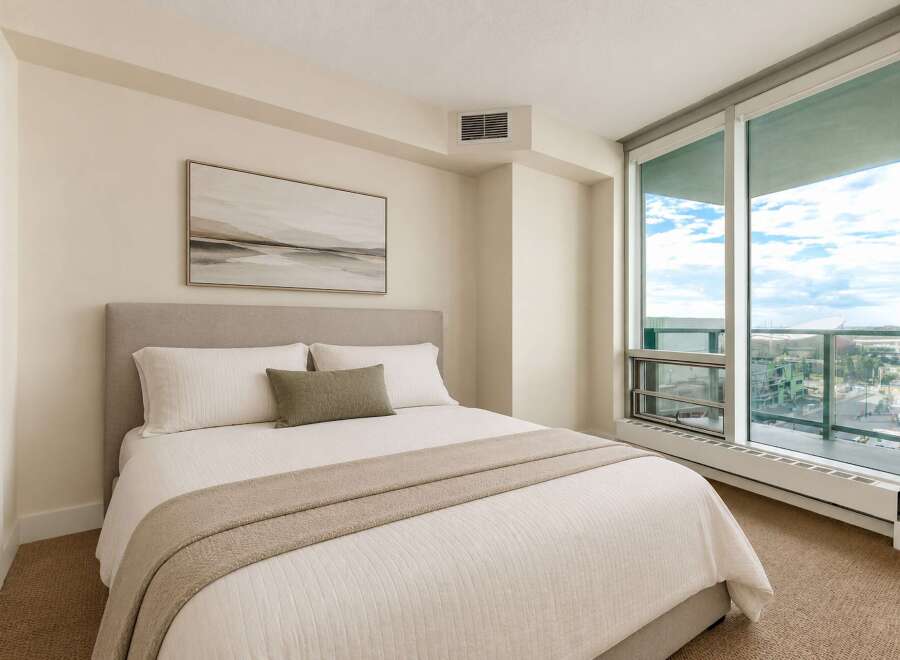 Experience modern living in this beautifully appointed bedroom, featuring a plush king-sized bed with crisp white linens and a decorative throw.