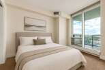 Experience modern living in this beautifully appointed bedroom, featuring a plush king-sized bed with crisp white linens and a decorative throw.