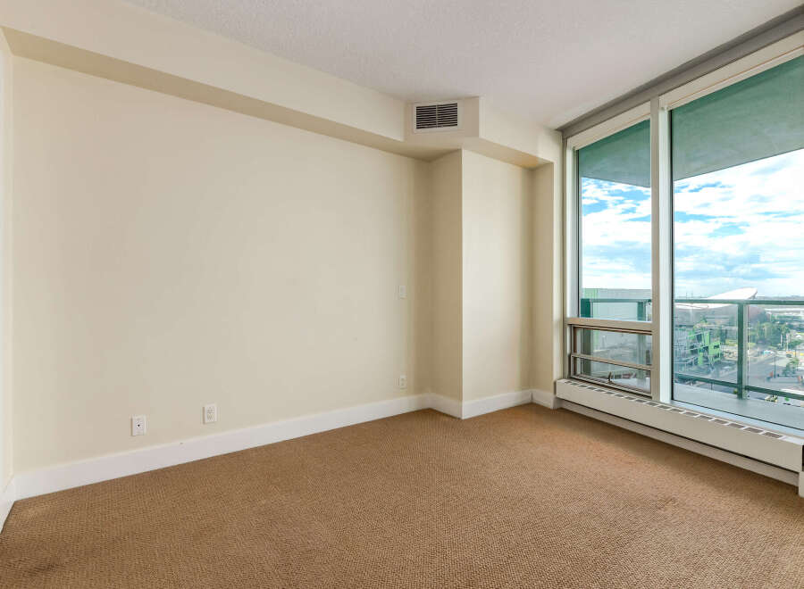 This empty room offers a blank canvas for your personal style, featuring neutral-toned walls and carpeting.