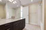 This modern bathroom features a sleek vanity with a marble countertop and dark wood cabinetry, complemented by a large mirror reflecting the shower area.