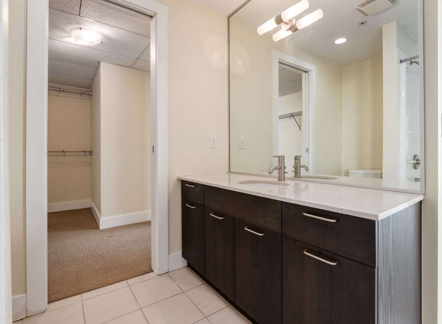 Discover modern comfort in this bathroom featuring a sleek vanity with dark wood cabinets and a white quartz countertop.