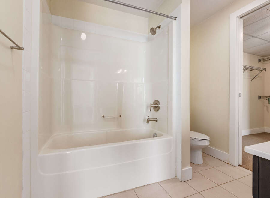 This bathroom features a pristine white bathtub and shower combination, complete with a modern chrome showerhead and faucet.