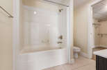This bathroom features a pristine white bathtub and shower combination, complete with a modern chrome showerhead and faucet.